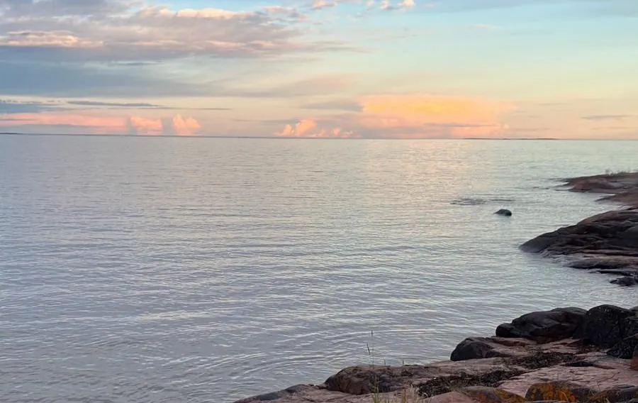 Pink granite shore and calm sea at dusk